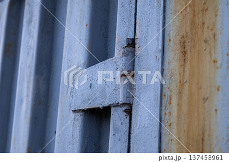 A metal gate is shown from a close angle, highlighting the texture and rust on the surface in a residential area during late afternoon light 137458961