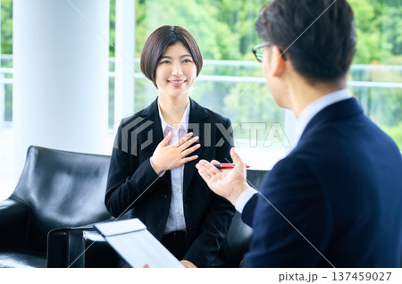 採用面接で自信を持って自己PRをするリクルートスーツの女性と話を聞く面接官の男性 137459027