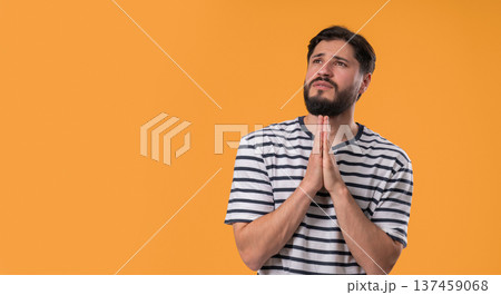 Bearded Man Praying With Fingers On Yellow, Copy space. Guy Begs Satisfy Desires 137459068