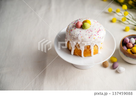 Easter festive cake with icing, sprinkles and eggs candy. White eggs and spring, yellow flower twigs. 137459088