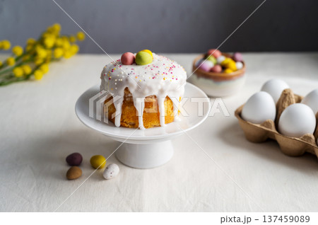 Easter festive cake with icing, sprinkles and eggs candy. White eggs and spring, yellow flower twigs. Easter festive cake with icing, sprinkles and eggs candy. White eggs and spring, yellow flower twigs. 137459089