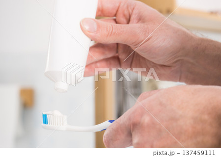 Person putting toothpaste on toothbrush 137459111