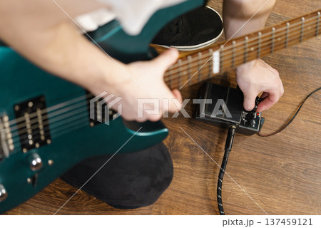 Man adjusting guitar effects pedal 137459121