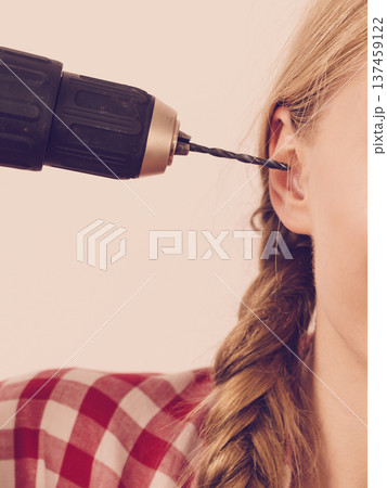 Woman pointing at her head with drill 137459122