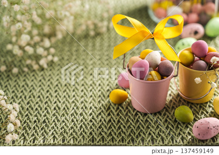 Easter holiday background. Mini chocolate egg candies in buckets with gypsophila flowers. Copy space 137459149