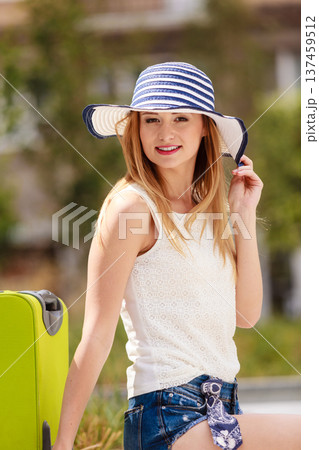 Attractive woman tourist with suitcase relaxing after trip Attractive woman tourist with suitcase relaxing after trip 137459512