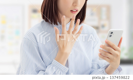 スマートフォンの画面を見て驚く女性・ビジネスウーマン スマートフォンの画面を見て驚く女性・ビジネスウーマン 137459822