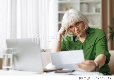 Senior woman looking worried while reading document at home 137459835