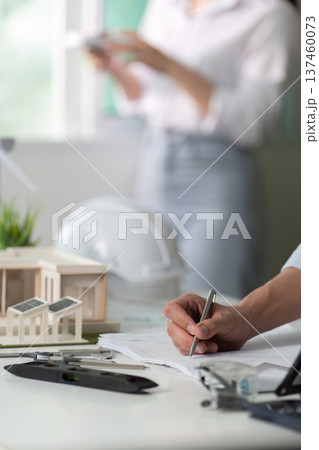 A man is writing on a piece of paper with a pen 137460073