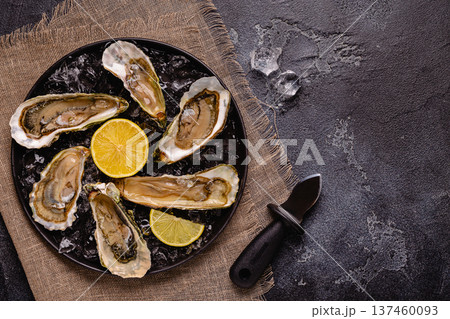 Opened fresh oysters on a plate, served with lemon and ice. Opened fresh oysters on a plate, served with lemon and ice. 137460093