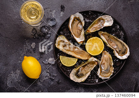 Opened fresh oysters on a plate, served with lemon and ice. Opened fresh oysters on a plate, served with lemon and ice. 137460094