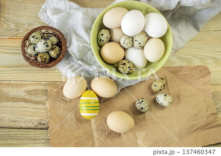 Easter, preparation for the holiday. Various colored and fresh chicken and quail eggs on a rustic wooden table. Easter, preparation for the holiday. Various colored and fresh chicken and quail eggs on a rustic wooden table. 137460347