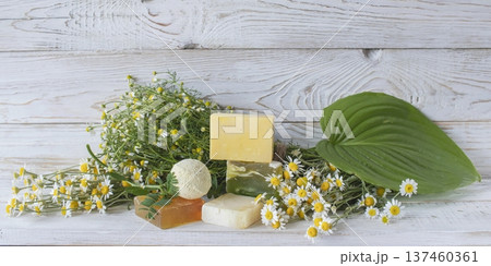 Natural handmade soap with chamomile and bath bomb. Natural handmade soap and chamomile flowers on a white wooden background. 137460361