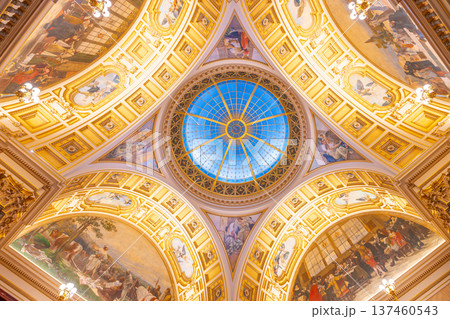 Visitors view the ornamental ceiling with a circular roof window in the Pantheon section of the National Museum of Prague. The design features various artistic elements and lighting. Visitors view the ornamental ceiling with a circular roof window in the Pantheon section of the National Museum of Prague. The design features various artistic elements and lighting. 137460543