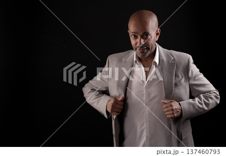 Confident African American businessman adjusting his jacket on black background Confident African American businessman adjusting his jacket on black background 137460793