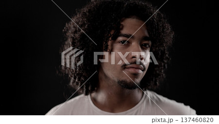 Young african-american man with curly hair posing on dark background 137460820