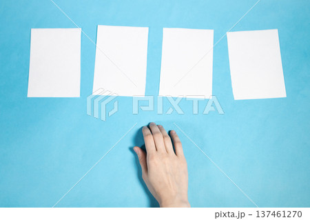 sheets of blank white paper on blue and hand sheets of blank white paper on blue and hand 137461270