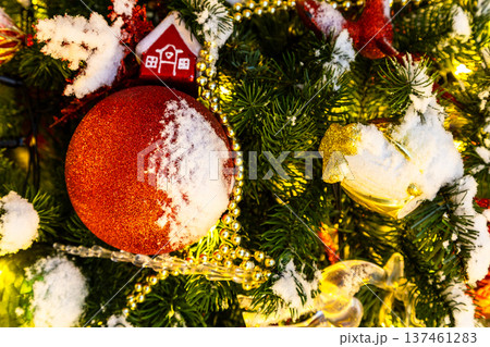 toys and garland on snow-covered christmas tree 137461283