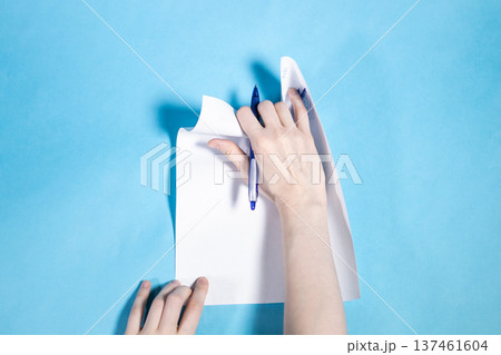 top view of hand with pen tears sheet of paper top view of hand with pen tears sheet of paper 137461604