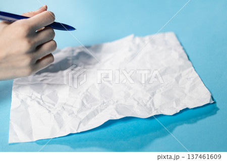hand with pen over crumpled sheet of paper hand with pen over crumpled sheet of paper 137461609