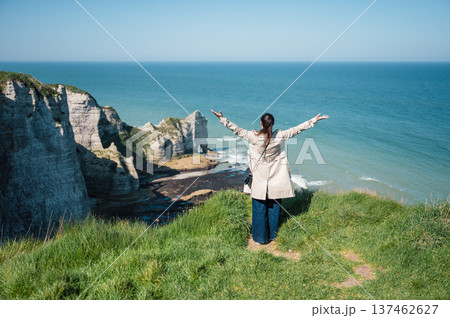 Woman stands and look at cliffs and Waters of Etretat Woman stands and look at cliffs and Waters of Etretat 137462627