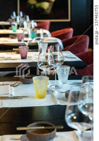 Stylish restaurant ambiance with colorful glassware. Closeup of wineglasses amid vibrant restaurant backdrop Stylish restaurant ambiance with colorful glassware. Closeup of wineglasses amid vibrant restaurant backdrop 137462755