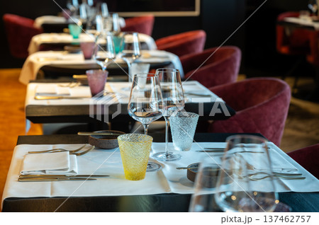 Symmetrical tables prepared meticulously for service featuring elegant glassware and professional ambiance Symmetrical tables prepared meticulously for service featuring elegant glassware and professional ambiance 137462757