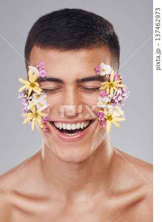 Skincare, man and flowers on face in studio, eyes closed and natural cosmetics for art, makeup product and wellness. Spring, person and closeup of floral decoration for facial on gray background Skincare, man and flowers on face in studio, eyes closed and natural cosmetics for art, makeup product and wellness. Spring, person and closeup of floral decoration for facial on gray background 137462973