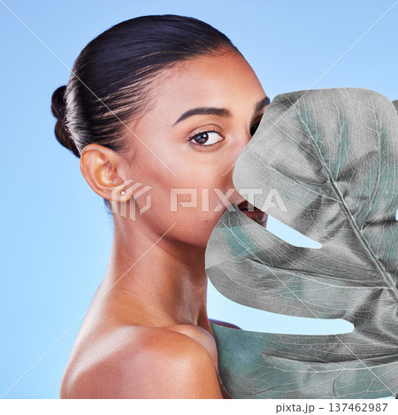 Leaf, skincare and portrait of woman in studio for eco friendly, wellness or cosmetics on blue background. Monstera, face and Indian female with natural dermatology, beauty or organic body care 137462987