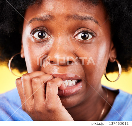 Anxiety, biting nails and a woman scared in studio with fear, mental health or nervous behaviour. Face portrait of African person on yellow background worried, stress or panic for phobia or horror Anxiety, biting nails and a woman scared in studio with fear, mental health or nervous behaviour. Face portrait of African person on yellow background worried, stress or panic for phobia or horror 137463011