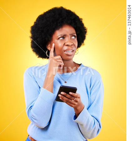 Confused, thinking and black woman with mobile for a chat, communication or an app. Website, contact and an African girl with doubt about an online message or web notification on a yellow background Confused, thinking and black woman with mobile for a chat, communication or an app. Website, contact and an African girl with doubt about an online message or web notification on a yellow background 137463014