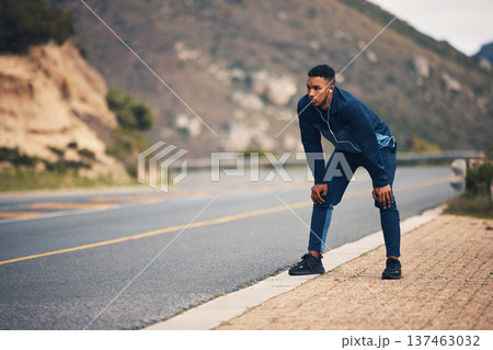 Tired runner man, mountain and rest with earphones, music and thinking for fitness, health and wellness in street. Guy, outdoor and training for marathon with fatigue, vision and burnout in nature 137463032