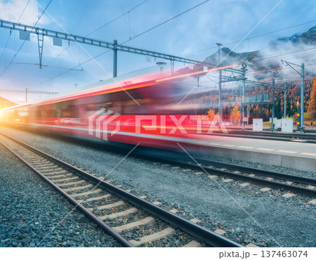Blurred red passenger train passing mountain railway station 137463074