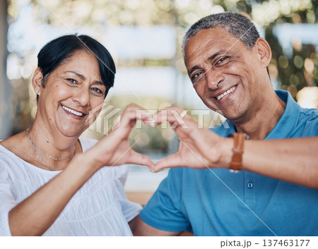 Portrait, hands and heart with a senior couple in the living room of their home together to relax. Face, smile or love with a happy elderly man and woman in the house for bonding or commitment 137463177