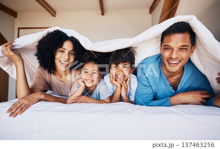 Happy, smile and portrait of a family with a blanket for relaxing, bonding or resting together. Happiness, love and young children with their parents from Colombia on the bed in room of their house. 137463256