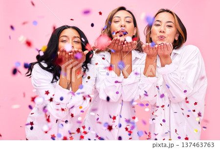 Blowing confetti, friends and women in studio for party celebration, fashion sale and discount. Bonding, diversity and happy people on pink background for support, natural beauty and retail promotion Blowing confetti, friends and women in studio for party celebration, fashion sale and discount. Bonding, diversity and happy people on pink background for support, natural beauty and retail promotion 137463763
