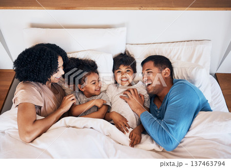 Family, funny and kids laughing in bed at home in the morning together with their happy parents. Relax, love or smile with a mother, father and children in a bedroom for weekend bonding from above 137463794