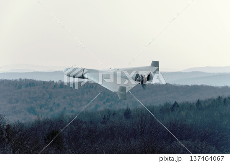Kamikaze attack drone flies above forest and hills during war. Kamikaze attack drone flies above forest and hills during war. 137464067
