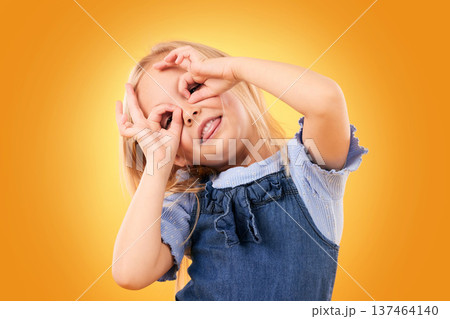 Kids, fun and hand glasses by girl in studio playing, free and funny gesture against orange background space. Finger, frame and child with silly expression, mood or personality, playful or games 137464140