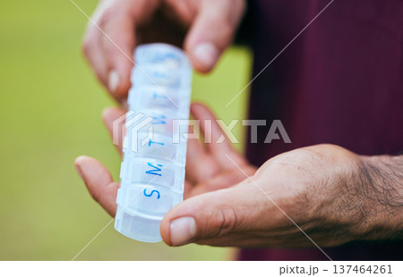 Pill box, weekly medicine and hand closeup of a sport athlete on a soccer field with tablet and drugs for health. Supplements, plastic container and outdoor with a man holding wellness and medication Pill box, weekly medicine and hand closeup of a sport athlete on a soccer field with tablet and drugs for health. Supplements, plastic container and outdoor with a man holding wellness and medication 137464261