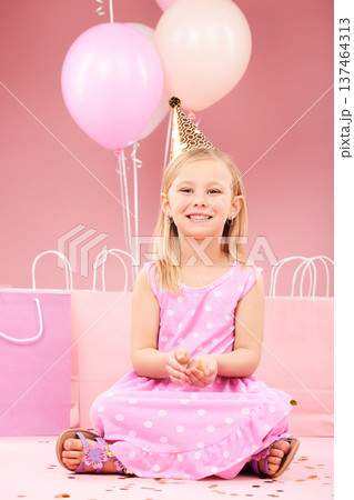 Balloons, birthday and portrait of girl in studio for party, celebration and special day. Happy, excited and young child sitting with presents, gift box and decoration for event on pink background 137464313