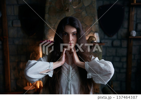 Expressive mystical portrait of contemplative woman amid candlelight and stone 137464387