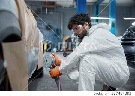 Technician sanding car body panel with orbital sander Technician sanding car body panel with orbital sander 137464393