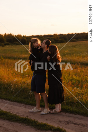 Family with little daughter standing in meadow at sunset Family with little daughter standing in meadow at sunset 137464947