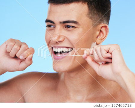 Happy man, face and dental floss in teeth cleaning, hygiene or grooming against a blue studio background. Male person or model smile with flossing in oral, tooth whitening or gum and mouth care Happy man, face and dental floss in teeth cleaning, hygiene or grooming against a blue studio background. Male person or model smile with flossing in oral, tooth whitening or gum and mouth care 137465718