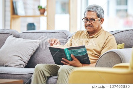 Home, relax and senior man with a book, retirement and calm with a story in a living room. Old person, calm and pensioner in a lounge, novel or literature with a hobby, self help or reading on a sofa 137465880