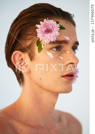 Beauty, petals and flowers on face of man in studio for spring, natural cosmetics and creative. Glow, self love and floral with model on white background for makeup, spa treatment and wellness 137466079
