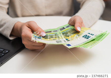 Close up of woman counting euro banknotes and entering data on laptop. Budget control, accounting, savings, freelance income and economic organization concept. 137466271