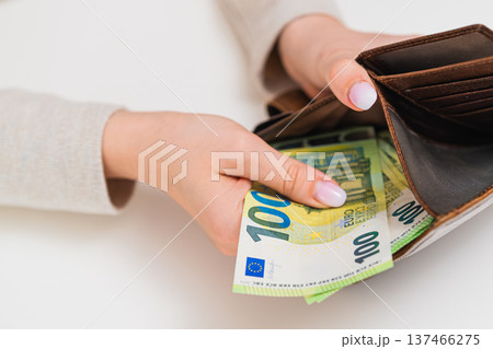 Woman placing 100 euro banknotes in brown wallet. Concept of budgeting, cash storage, income, payment, financial responsibility and money security in EU. Woman placing 100 euro banknotes in brown wallet. Concept of budgeting, cash storage, income, payment, financial responsibility and money security in EU. 137466275