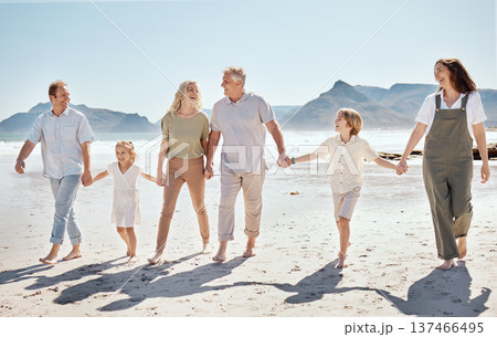 Happy, walking and big family holding hands at the beach on vacation, holiday or adventure together. Bonding, fun and children with parents and grandparents by the ocean for fresh air on weekend trip 137466495